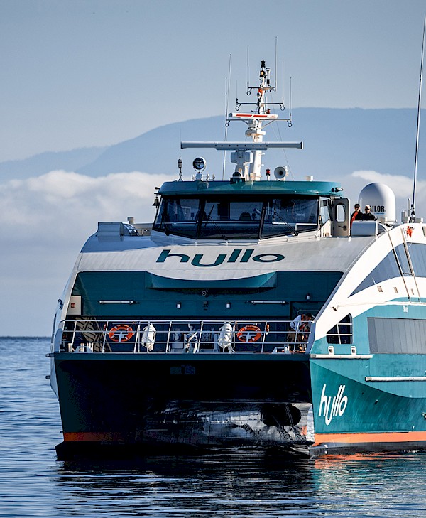A Hullo ferry boat on a calm sea with a mountain range faintly visible in the background