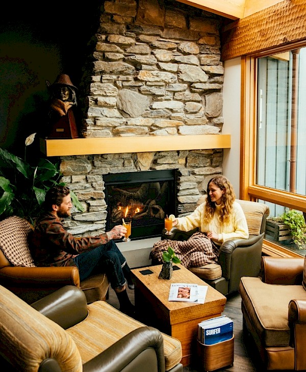 Two guests enjoying a warm drink by the fire in the Shoreline Terrace on a stormy day