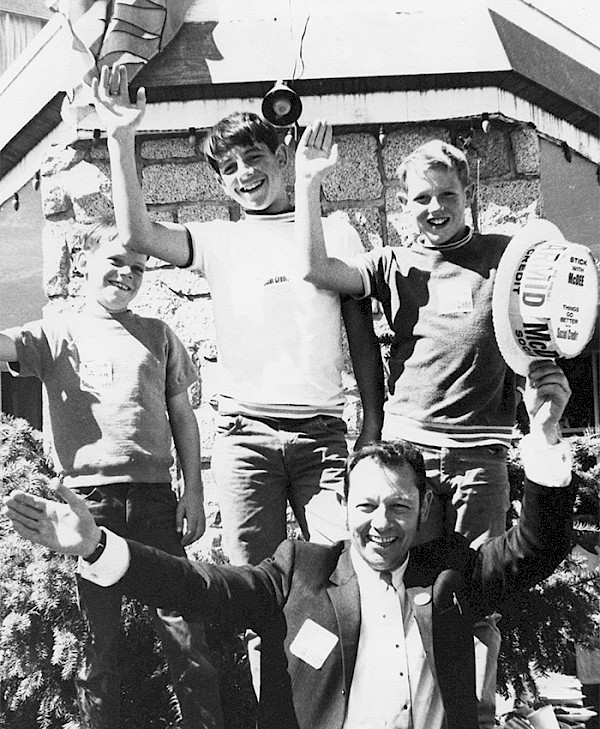 Dr. Howard McDiarmid smiling with three boys cheering beside him