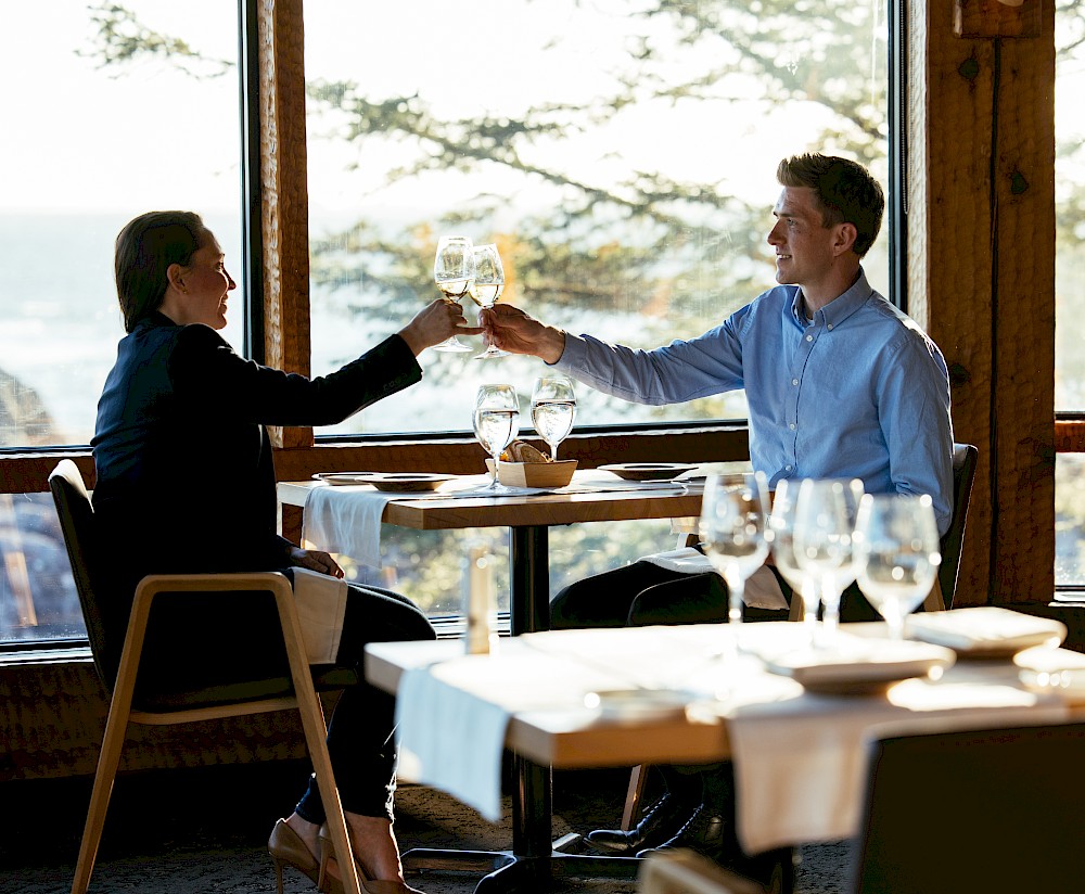 Couple toasting with wine at a window table overlooking the ocean at The Pointe Restaurant