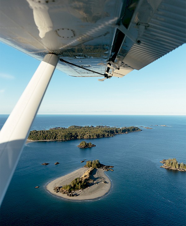 Aerial view of small forested islands and sandy spits taken from a floatplane wing